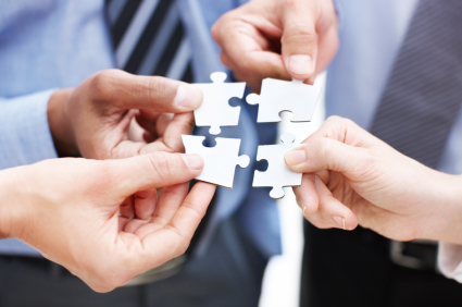 Closeup of businesspeople about to put four puzzle pieces together
